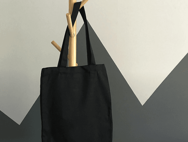 En takse hænger på en stumtjener med en grå og lys væg i baggrunden.